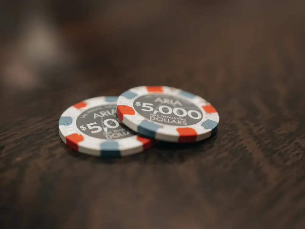 Two casino chips on a dark wooden table